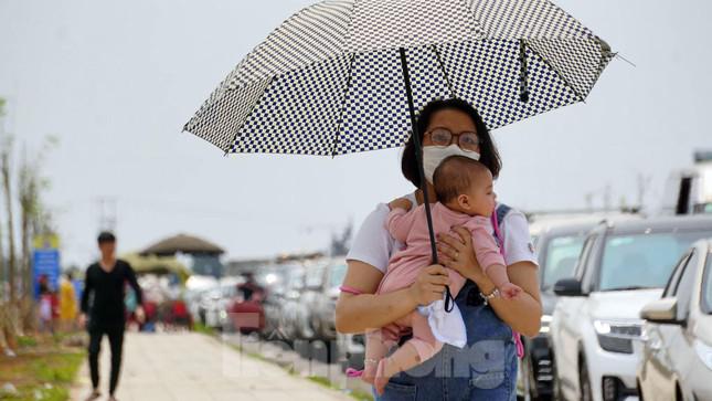 Một nữ du khách bế con nhỏ rời ô tô đi bộ hàng trăm mét đến điểm chờ lên phà để tránh nóng.