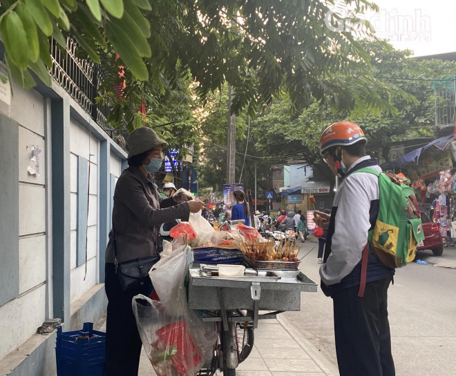 Em học sinh này dù đã đội mũ bảo hiểm để chuẩn bị đi về nhưng vẫn nán lại ăn thêm vài que xiên.