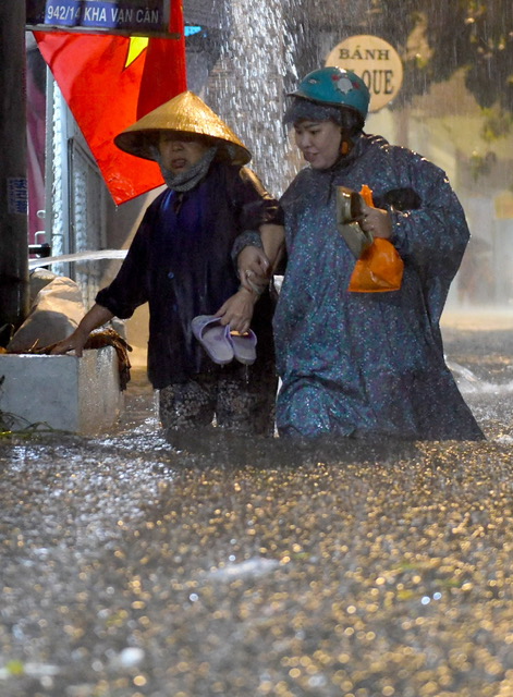 Hai người phụ nữ phải dìu nhau lội vùng nước ngập quá đầu gối trên đường Kha Vạn Cân.