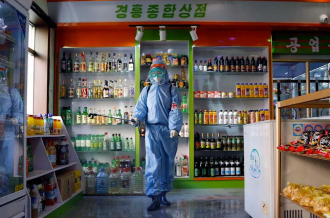 Một nhân viên y tế phun khử khuẩn phòng Covid-19 trong một cửa hàng ở Bình Nhưỡng. Ảnh: AP
