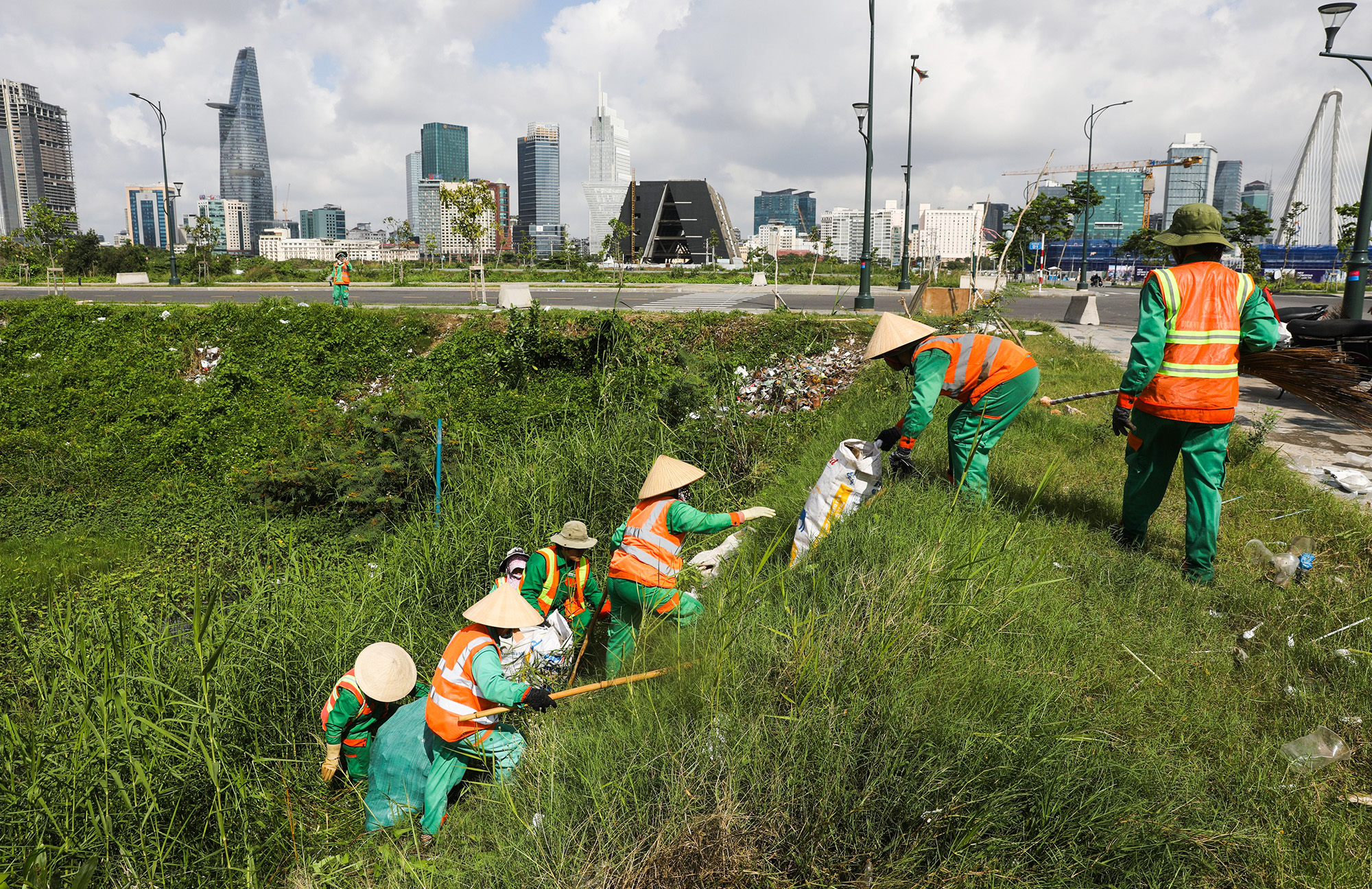 Công nhân thu gom rác khá vất vả để đem những bao rác từ dưới mép hồ lên đường do địa hình không bằng phẳng.