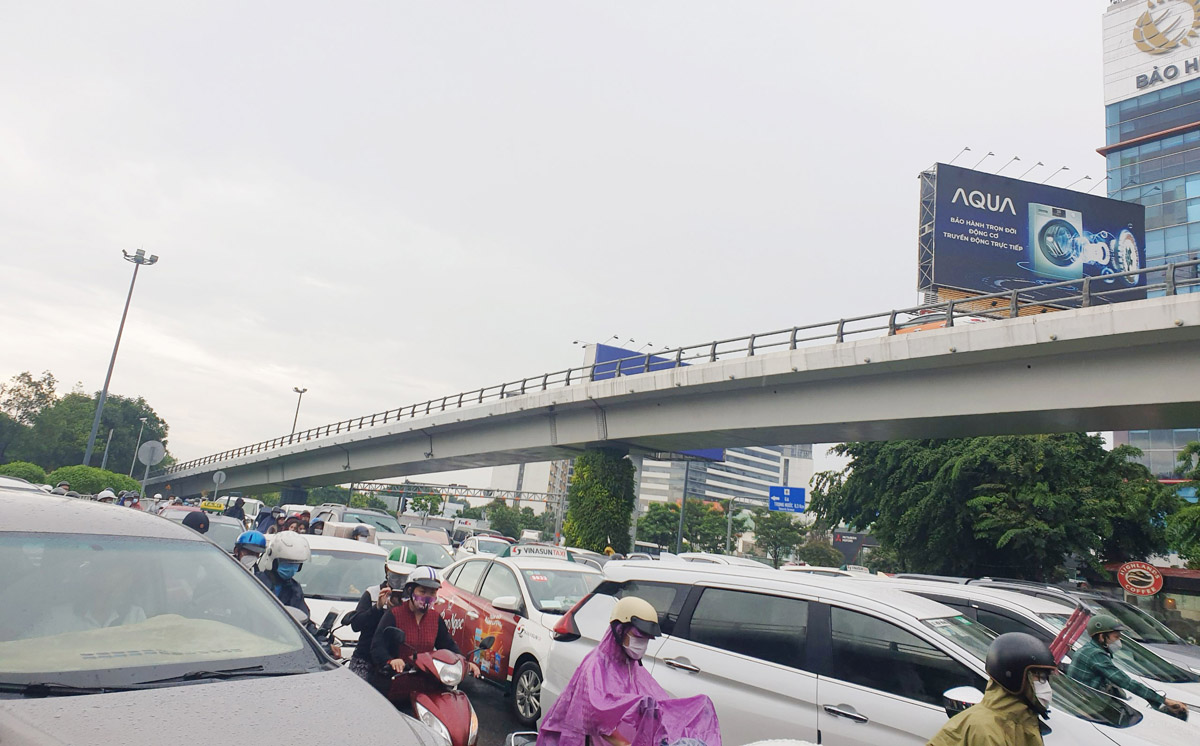 Đường Trường Sơn đoạn trước cổng sân bay Tân Sơn Nhất giao thông rối loạn. Người đi xe máy phải chen vào khoảng trống giữa các ô tô để di chuyển.