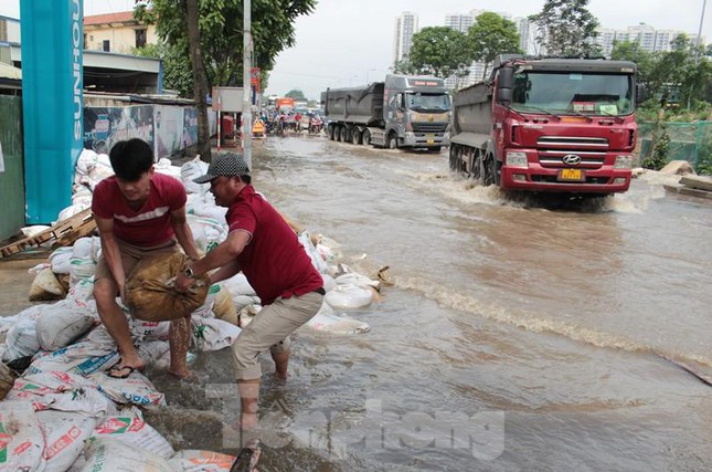 Nước ngập trên đường gom vẫn sâu và tạo sóng cao, có nguy cơ dâng vào nhà, một số hộ dân đã dùng bao tải cát làm bờ bao.