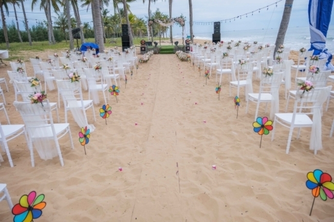 Buổi lễ có sự tham gia của hơn 200 khách mời. Không gian tiệc cưới được trang trí nhiều hoa, ghế cho khách mời màu trắng được sắp xếp ngay ngắn gọn gàng, sân khấu nằm trên bãi cát gần biển được thiết kế đơn giản nhưng sang trọng và đẹp mắt. Lối đi lên sân khấu được cắm nhiều hoa và chong chóng.

