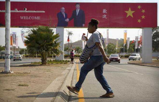 Người dân băng qua đường gần bảng chào đón chuyến thăm của Chủ tịch Trung Quốc Tập Cận Bình ở Port Moresby, Papua New Guinea, ngày 15-11-2018. Ảnh: AP