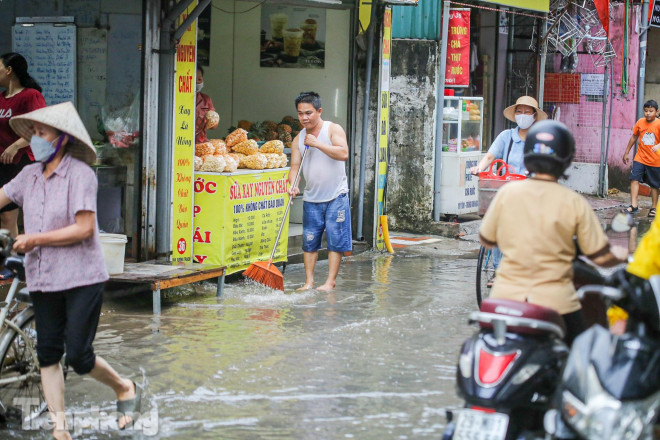 Người dân dùng chổi quét - gạt để nước không bị tràn vào nhà.