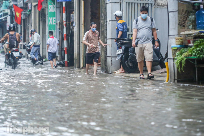 Nước tràn vỉa hè khiến người đi bộ di chuyển khó khăn.