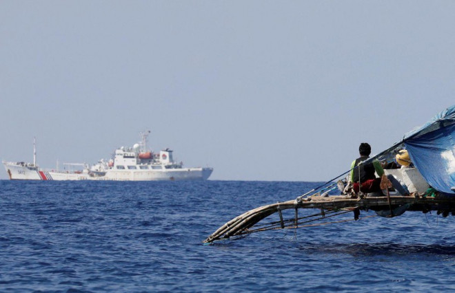 Một ngư dân Philippines quan sát tàu Cảnh sát biển Trung Quốc tuần tra gần bãi cạn Scarborough. Ảnh: REUTERS
