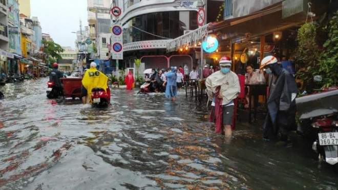 Nhiều người bì bõm lội nước đi qua phố đi bộ Bùi Viện khi trời mưa lớn.