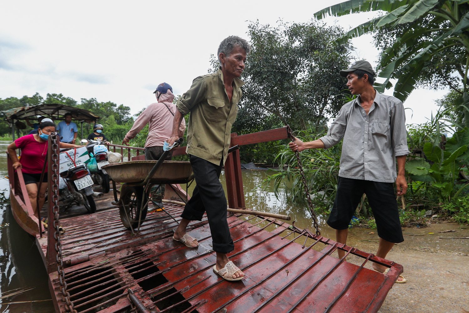 Ông Dũng đang kéo giúp người dân xe cút kít xuống đò. Ông cũng là người duy nhất còn lái đò chở người ở đây khi nước ngập, đến nay đã được hơn 20 năm.