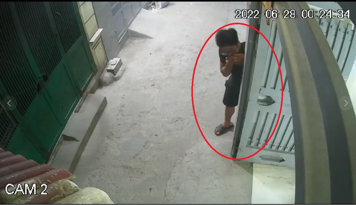 Nam thanh niên đeo kính núp bên hông cửa khi cô gái trẻ đi vào khu nhà trọ (Ảnh cắt từ clip)