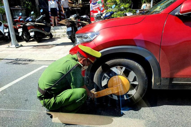 Công an TP Nha Trang đang khóa bánh xe một ô tô vi phạm đỗ xe trên đường Yersin vào ngày 11-6. Ảnh: HUỲNH HẢI