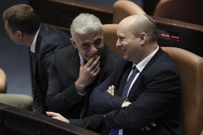 Cựu thủ tướng Naftali Bennett (phải) và tân thủ tướng lâm thời Yair Lapid tại Quốc hội Israel ngày 30-6 - Ảnh: AP