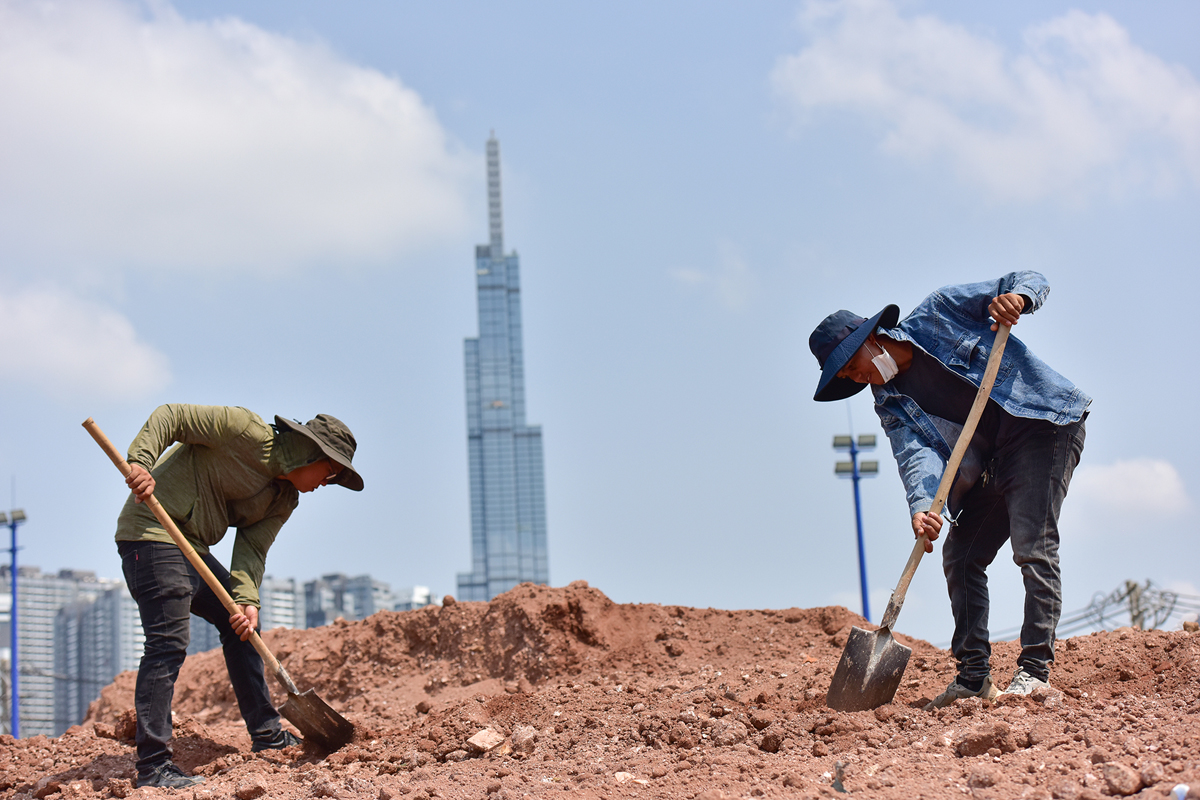 Giữa trưa, anh Nguyễn Văn Vũ cùng nhóm hàng chục công nhân đội nắng thi công nhiều hạng mục vòng xoay nút giao thông đường Lương Định Của - Trần Não.