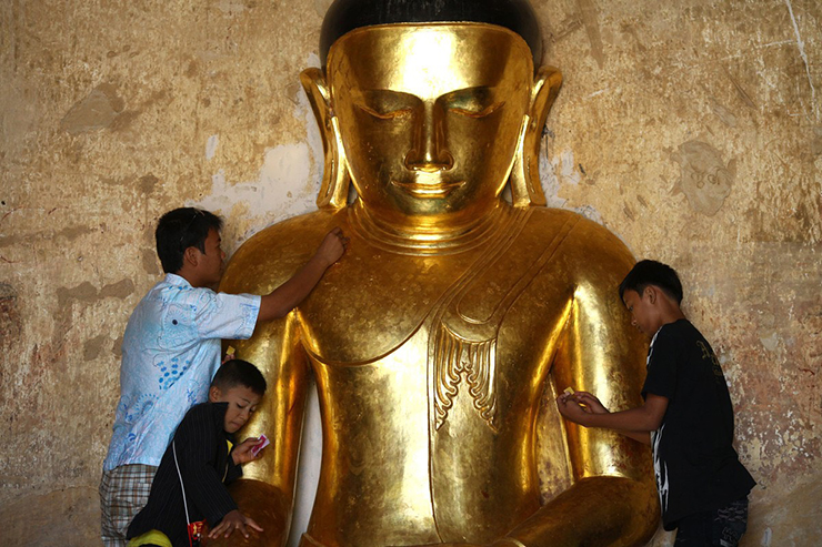 Các cậu bé dát vàng lá lên tượng Phật tại một ngôi chùa ở Bagan.
