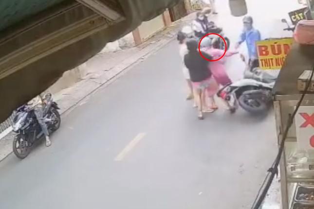 Chị H (khoanh tròn đỏ) bị nhóm người lôi ra khỏi xe máy để đánh (Ảnh cắt từ clip).