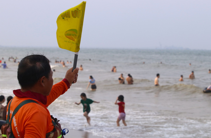 Đứng trên bờ, ông Tài Hùng (đội cứu hộ biển) liên tục phất cờ và thổi còi cảnh báo những du khách ra ngoài xa tắm. "Nếu thấy có người ra xa thì cảnh báo. Nếu có người đuối nước, gần thì mình bơi ra cứu. Xa thì báo cho cứu hộ, đội môtô nước chạy đến cứu ngay", ông Hùng nói.