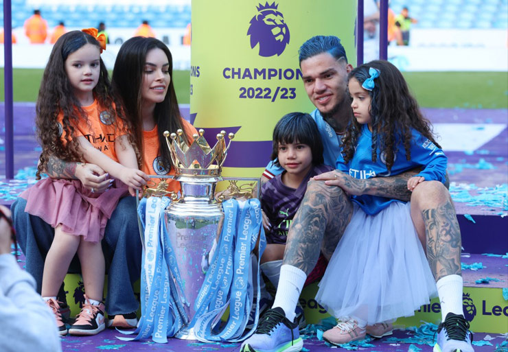 Ederson Moraes giơ 5 ngón tay tương ứng với 5 chức vô địch giải Ngoại hạng Anh đã có cùng Man City ở 6 mùa giải gần nhất khi chụp ảnh cùng người vợ xinh đẹp Lais Moraes và 3 con của họ