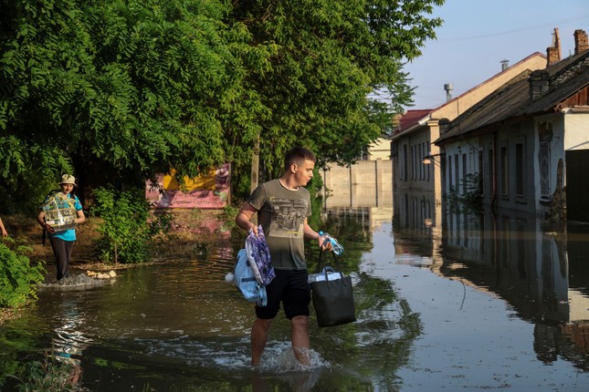 Người dân đưa đồ đạc ra khỏi vùng ngập lụt. Ảnh: Reuters