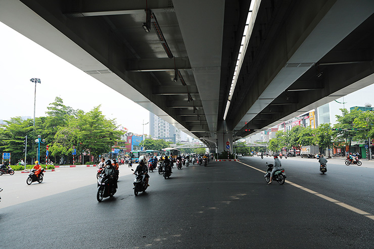 Thời điểm giữa trưa, rất nhiều người đi xe máy đi vào phần bóng râm từ đường trên cao tỏa xuống.
