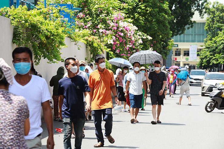 Dòng người đi bộ từ bệnh viện ra bên ngoài mua đồ ăn và các vật dụng thiết yếu cho bệnh nhân ở cổng sau Bệnh viện Bạch Mai.
