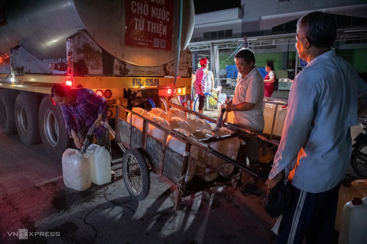 Nhiều người dùng xe đẩy để chở được nhiều nước. Ông Lê Văn Hứa (góc phải) cho biết phải chở hai xe đẩy nước mới đủ dùng cho gia đình mỗi ngày.