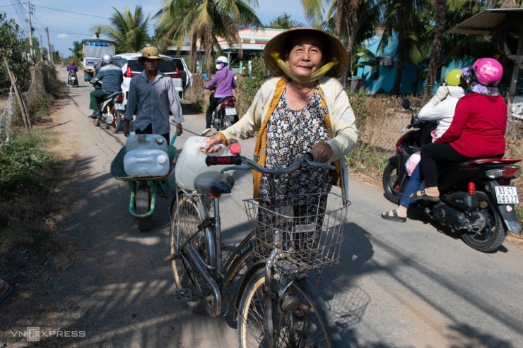 Nhiều người lớn tuổi dùng xe máy, xe đẩy chở nước về nhà.