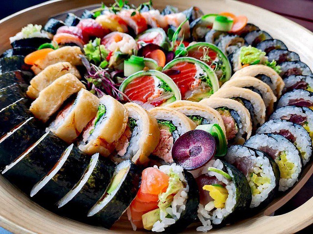 Việc nhúng dao qua nước trước khi cắt sushi giúp cuộn cơm đẹp mắt hơn. Món ăn được dùng kèm với nước tương Nhật, mù tạt và gừng đỏ ngâm chua. Sự kết hợp của hạt cơm dẻo, thấm gia vị, hải sản tươi ngọt, rong biển bùi bùi lôi cuốn vị giác thực khách. Ảnh: Koisushibarzwycieska.