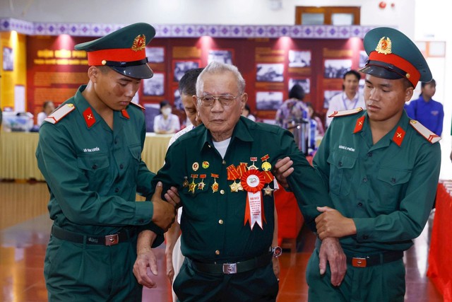 Các chiến sĩ trẻ hôm nay cùng những chiến sĩ Điện Biên năm xưa vào hội trường - Ảnh: Quang Vinh