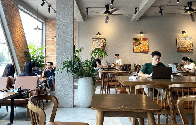 Nhóm bốn bạn trẻ (bên tay phải) chọn vị trí ngồi tách biệt với nơi nhiều người đang làm việc, để dễ nói chuyện, tại một quán cà phê ở quận Cầu Giấy, Hà Nội, chiều 12/4. Ảnh: Quỳnh Nguyễn