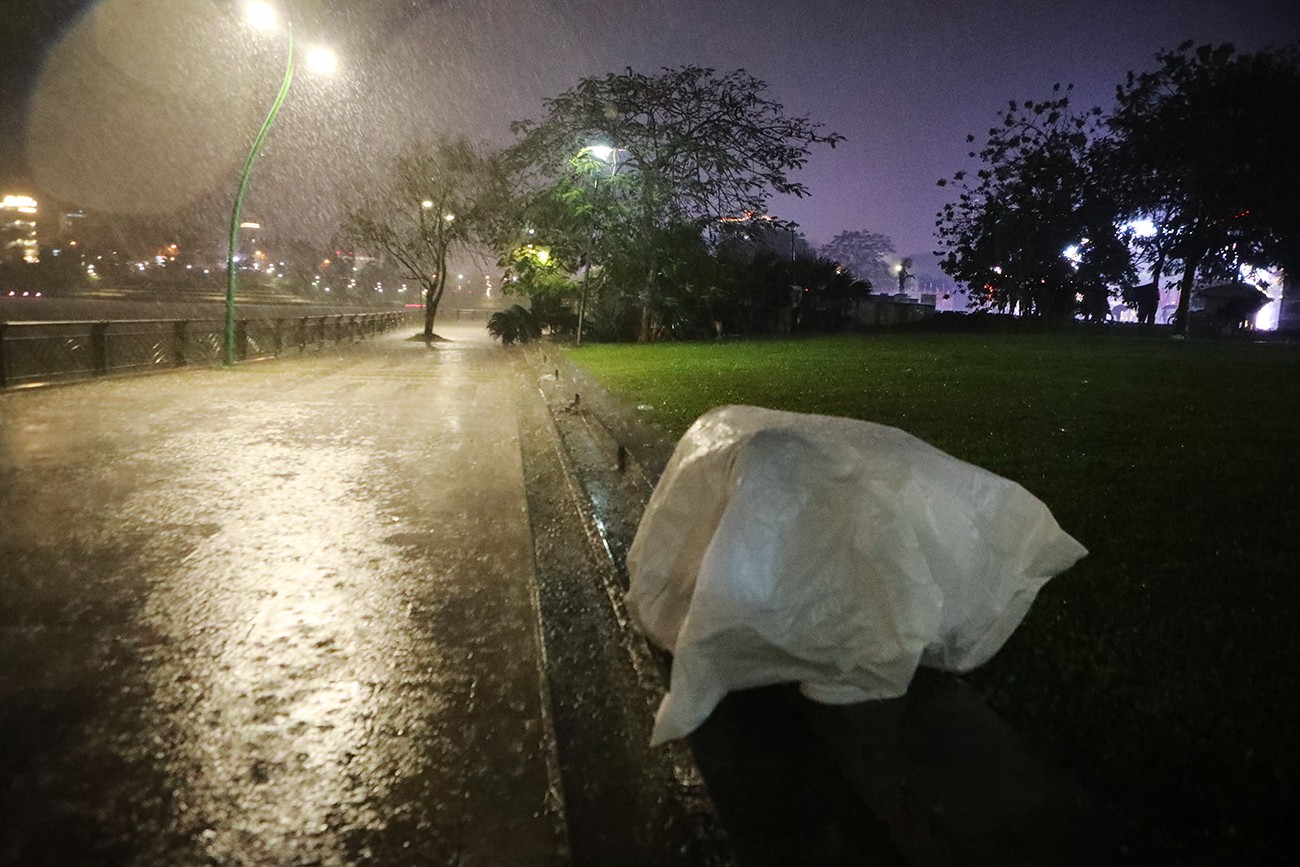 Một nhóm người dùng bạt phủ kín dưới mưa.
