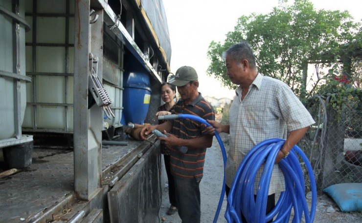 Ông Nguyễn Văn Hùng (áo trắng) hỗ trợ đem ống nước để bơm trữ nước cho người dân. Ảnh: HD