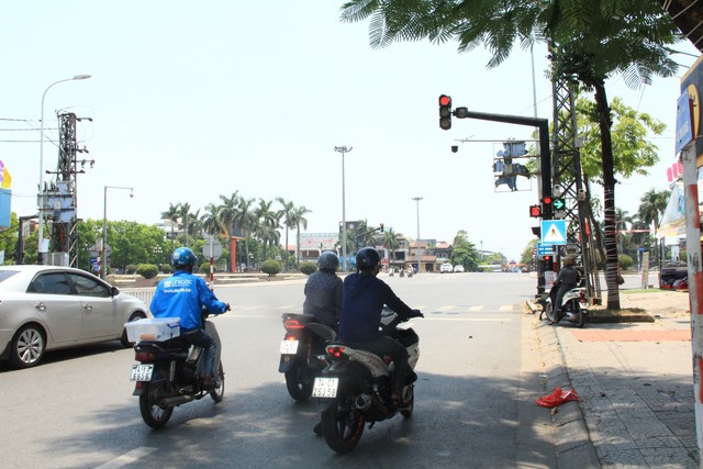 Tài xế xe ta-xi tận dụng bóng râm ít ỏi của cây xanh để "trốn nắng", trong khi người tham gia giao thông tìm bóng râm để chờ đèn đỏ.