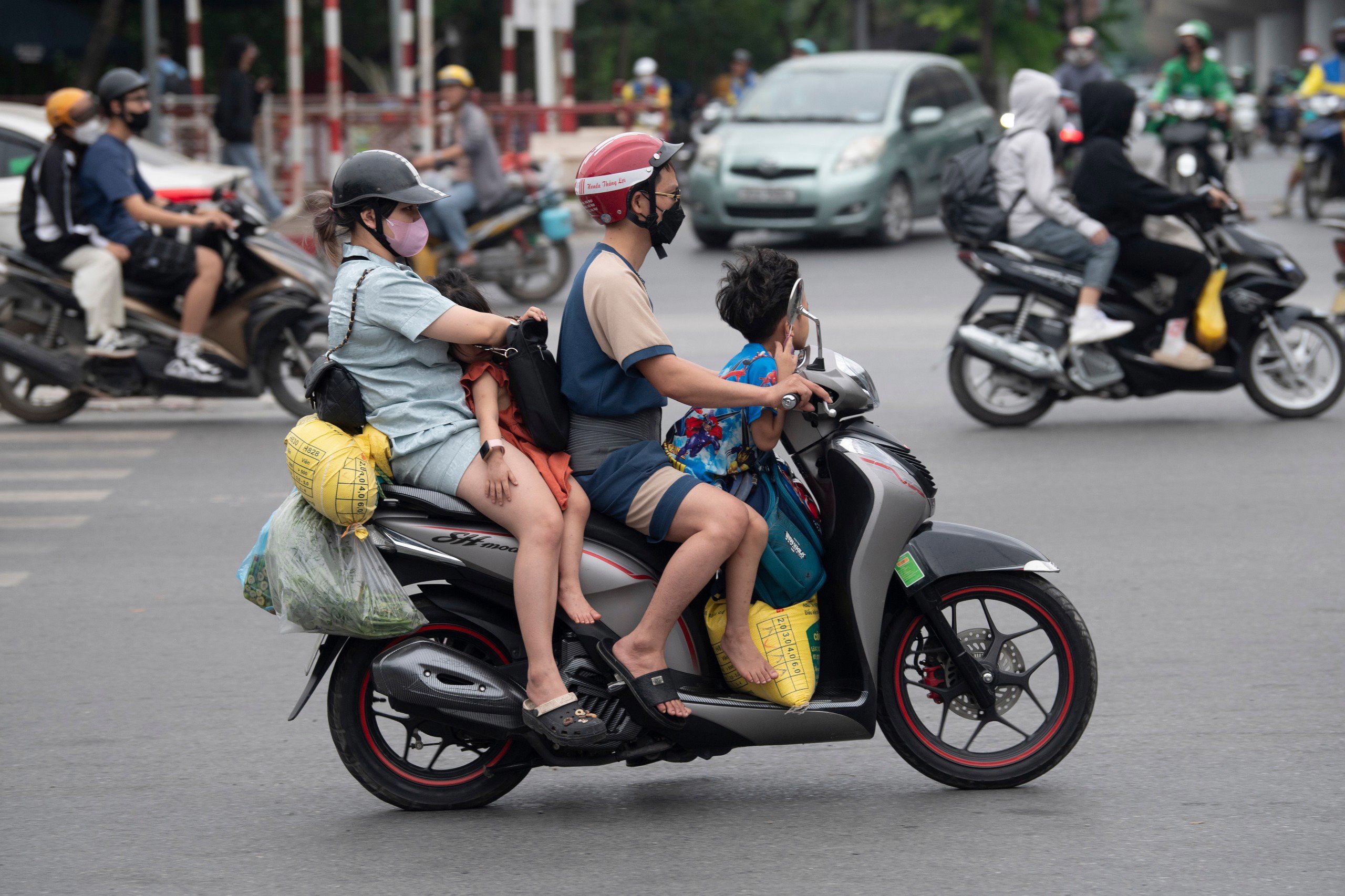 Gia đình 4 người trở lại Hà Nội trên chiếc xe máy với kỉnh kỉnh đồ đạc và cả một túi rau buộc phía đuôi xe.