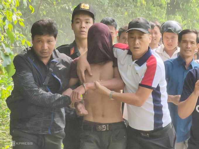 Cảnh sát bắt Tâm (bị trùm mặt) trong rừng keo, trưa 9/1. Ảnh: Đình Văn