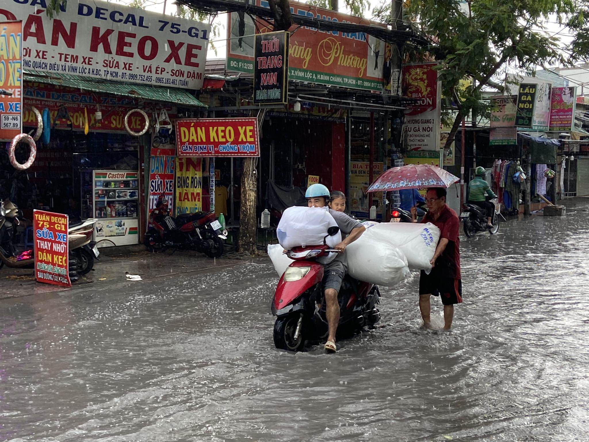 Người chở hàng di chuyển khó khăn trong nước ngập trên đường Quách Điêu. “Đây có lẽ là trận mưa lớn nhất từ đầu năm đến giờ. Hổm giờ trông mưa to quá chừng. Giờ mưa to, mừng quá mà đường ngập trong nước hôi thối thế này thì cũng ngán lắm”, anh Đông Lực ngụ huyện Bình Chánh nói.