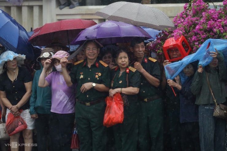 Cựu binh, người dân chờ diễu binh tại ngã tư Hoàng Văn Thái - Võ Nguyên Giáp. Ông Bùi Ngọc Sang, quê Thái Bình, một cựu binh chống Mỹ nói với những người xung quanh là "mưa cũng quyết tâm không bỏ chốt".