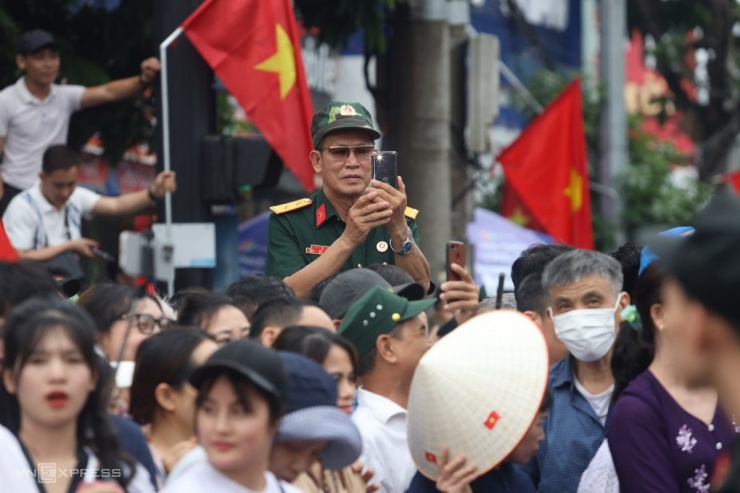 Một cựu binh dùng điện thoại ghi hình kỷ niệm trên đường phố Điện Biên Phủ.