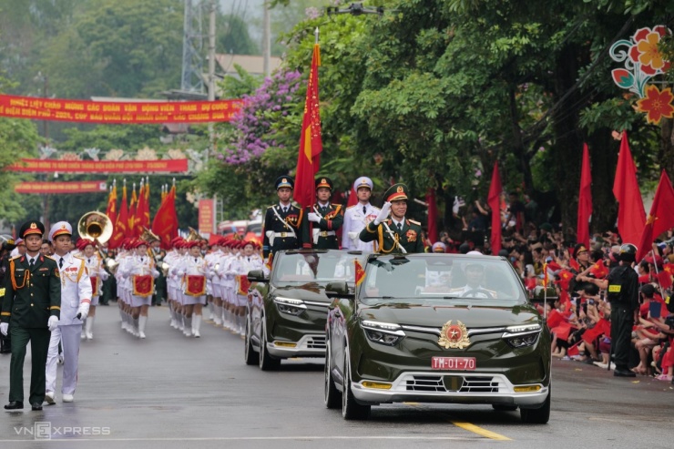 Sau khi rời sân vận động tỉnh Điện Biên, 40 khối đi đầu là xe mô hình Quốc huy, đi cuối là khối nghệ thuật lần lượt diễu binh, diễu hành qua một km đường Hoàng Văn Thái. Đến ngã tư Hoàng Văn Thái - Võ Nguyên Giáp, các quân binh chủng chia làm ba đoàn. Một đoàn rẽ phải qua đường Võ Nguyên Giáp, đi qua các di tích đồi A1, quảng trường 7/5, tượng đài chiến thắng Điện Biên Phủ. Một đoàn đi thẳng về cầu Mường Thanh. Đoàn còn lại rẽ trái đi qua Bảo tàng chiến thắng lịch sử Điện Biên Phủ. Trong ảnh là trung tướng Nguyễn Trọng Bình, Phó tổng Tham mưu trưởng Quân đội nhân dân Việt Nam, chỉ huy, dẫn đầu các khối đại diện cho Quân đội nhân dân và Dân quân tự vệ chào người dân hai bên đường.