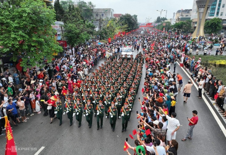 Các đoàn khối công an, quân đội diễu hành trên đường Võ Nguyên Giáp trong tiếng reo hò, cổ vũ cờ hoa của người dân hai bên đường.