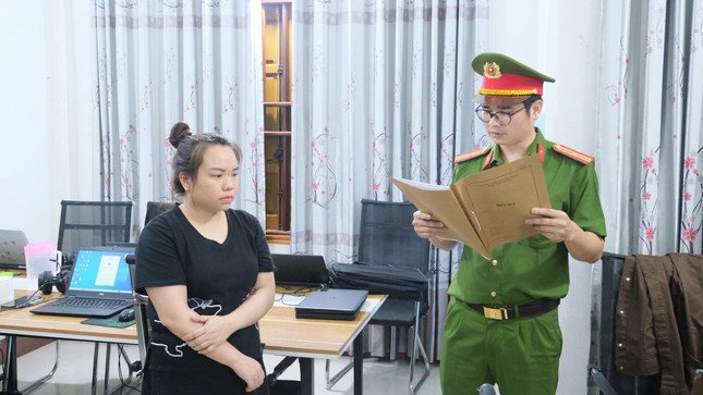 Đối tượng Nguyễn Thị Tuyết Dâng (bìa trái) nghe lệnh tạm giữ người để điều tra.