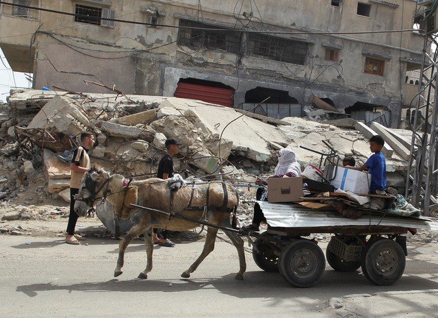 Người Palestine sơ tán qua những dãy nhà đổ nát vì bị không kích ở TP Rafah hôm 11-5 - Ảnh: REUTERS