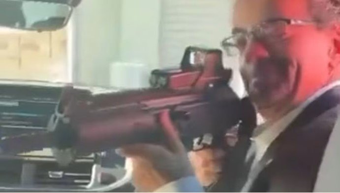 Ảnh cắt từ video cho thấy ông Jon Benjamin chĩa súng vào một nhân viên sứ quán. Ảnh: X