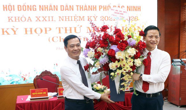 Phó Chủ tịch Thường trực UBND tỉnh Bắc Ninh Vương Quốc Tuấn (bên phải) tặng hoa chúc mừng ông Hiếu.