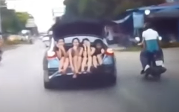 Ôtô chở bốn cô gái ngồi ở cốp sau chạy qua thị trấn Hóa Thượng. Ảnh cắt từ video