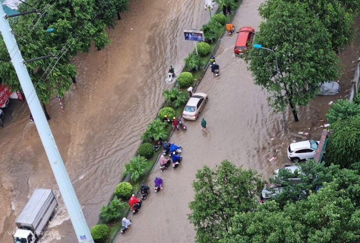 Người dân dắt xe đi bộ trên đường Tố Hữu (quận Hà Đông) sau cơn mưa sáng nay. Ảnh: Hoàng Minh Luyện