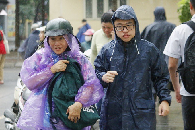 Phụ huynh đưa con đi thi lớp 10 trong trời mưa tầm tã, sáng 5/6. Ảnh: Thanh Hằng