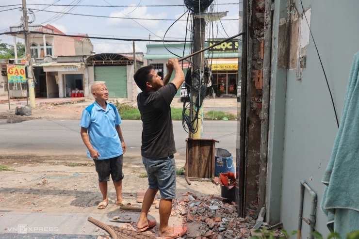 Cách đó vài căn, ông Phạm Chí Thành thuê thợ tháo phần cửa cuốn cũ, sau khi đã bàn giao 48 m2 đất cho dự án. "Tôi chưa thống nhất mức đền bù nhưng cứ chấp nhận bị giải toả đất trước đã. Mong bà con quanh đây cũng sớm bàn giao mặt bằng để dự án nhanh về đích", người đàn ông 75 tuổi nói.