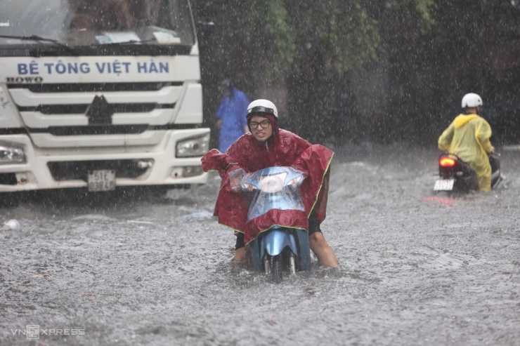 Đường ngập sâu, xe chết máy, người dân cố đẩy phương tiện để tránh những đợt sóng lớn khi ôtô đi qua.