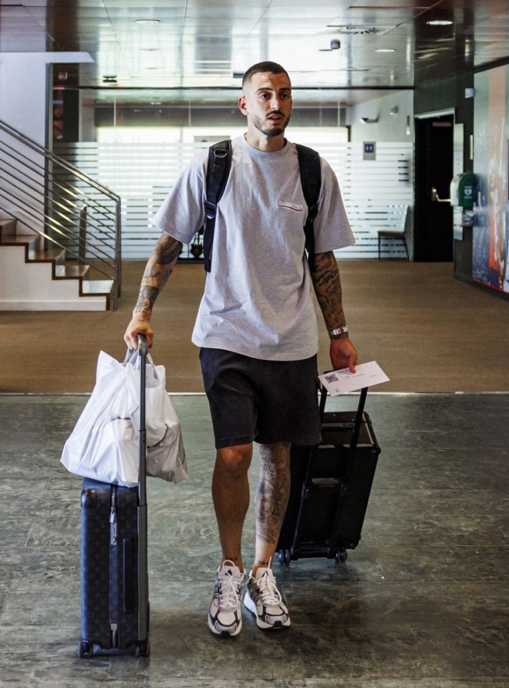 Tiền đạo Joselu Mato (Real Madrid) mặc năng động gồm áo thun Balenciaga, quần shorts lửng, giày thể thao. Cặp vali kéo và balo đều của Louis Vuttion.